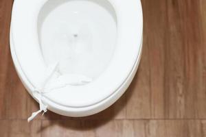 closeup of a young man throwing a wet wipe to the toilet, in a white tiled restroom photo