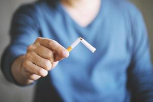 Portrait of man holding broken cigarette in hands. Happy man quitting smoking cigarettes photo