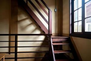 antigua escalera de madera junto a la ventana. sombra interior de la luz natural que pasa por la ventana. foto