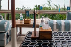 Dining table in the restaurant. Alcohol gel hand sanitizer served on the table in pandemic period. photo