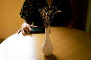 The girl in leisure time with her smart phone, vase in front of her, dramatic scene. photo