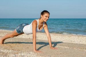 mujer joven practicando yoga o fitness en la orilla del mar foto