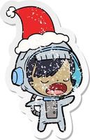 distressed sticker cartoon of a talking astronaut woman wearing santa hat vector