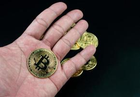 moneda bitcoin colocada en la mano sobre un fondo negro foto