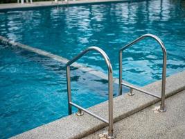 Escaleras de acero inoxidable a la piscina. Pasamanos arriba y abajo de la piscina. foto