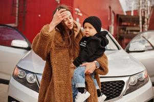 la joven madre y el niño se paran cerca de su auto todoterreno. concepto de conducción segura. foto