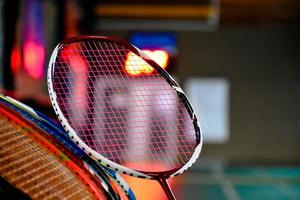 raquetas de bádminton para jugar al bádminton en una cancha de bádminton interior con sombreado de luz de neón en el suelo verde, fondo de bádminton borroso, espacio para copiar. foto