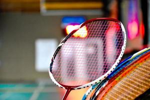 raquetas de bádminton para jugar al bádminton en una cancha de bádminton interior con sombreado de luz de neón en el suelo verde, fondo de bádminton borroso, espacio para copiar. foto