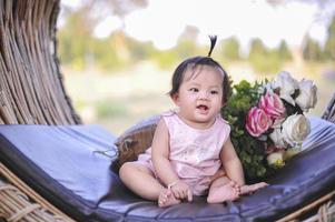 niña asiática con felicidad, retrato niño pequeño de 8 meses sentado con vestido rosa y sonriendo feliz. foto