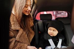 Young mother and child in car. Baby seat on chair. Safety driving concept. photo