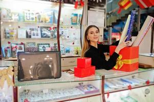 retrato de una joven vendedora caucásica empaca una bolsa de regalo. pequeña empresa de tienda de souvenirs de dulces.