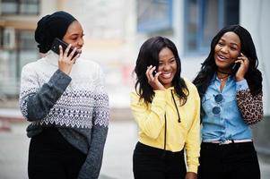 tres jóvenes universitarias amigas afroamericanas con teléfonos móviles. foto