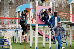 Young millennials african friends on playground, slide and swing. Happy black people having fun together. Generation Z friendship concept. photo