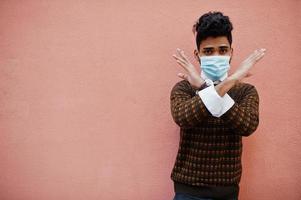 Coronavirus covid-19 concept. South asian indian man wearing mask for protect from corona virus isolated on pink background. photo