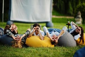 Young multi ethnic group of people watching movie at poof in open air cinema. photo