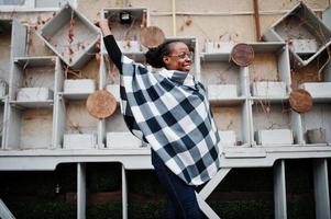 African woman in checkered cape and eyeglasses posed outdoor. photo