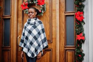 African woman in checkered cape posed outdoor against christmas decorations. photo