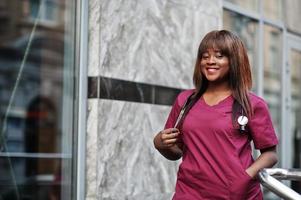 African american female doctor at red lab uniform with stethoscope. Medicine, profession and healthcare concept. photo