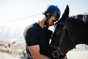 Arab tall beard man wear in black helmet with arabian horse. photo