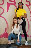 White caucasian girl and black African American together against graffiti wall. World unity, racial love, understanding in tolerance and races diversity cooperation. photo