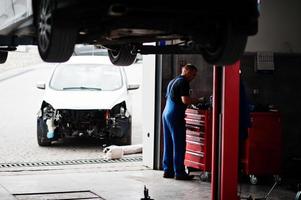 Car repair and maintenance theme. Mechanic in uniform working in auto service. photo