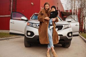 Young mother and child stand near they suv car. Safety driving concept. photo