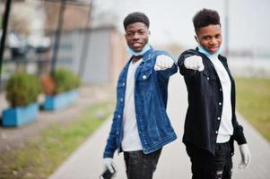 Two african teenagers friends at park wearing medical masks protect from infections and diseases coronavirus virus quarantine. photo