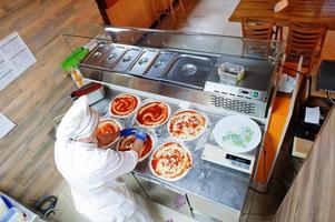 cocinera preparando pizza en la cocina del restaurante. foto