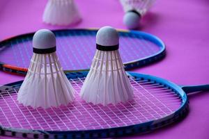 badminton shuttlecock and racket with neon light shading on green floor in indoor badminton court, blurred badminton background, copy space. photo