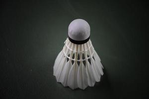 White badminton shuttlecock on dark floor of the badminton court. photo