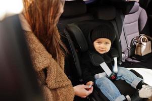 Young mother and child in car. Baby seat on chair. Safety driving concept. photo