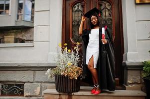 Young female african american student with diploma poses outdoors. photo