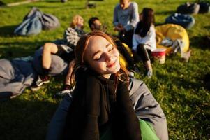 Young multi ethnic group of people watching movie at poof in open air cinema. Close up portrait of funny girl. photo