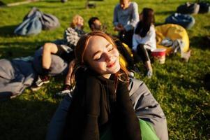 joven grupo multiétnico de personas viendo películas en poof en cine al aire libre. Cierra el retrato de una chica divertida. foto