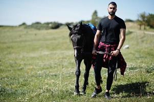 Arab tall beard man wear in black with arabian horse. photo