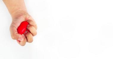 The hand was squeezing the red heart until it flattened. Depict an angry mood On a white background photo