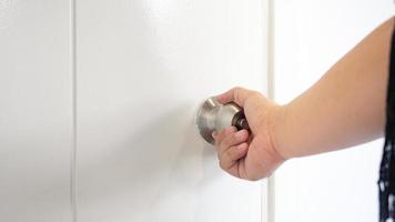 Man's hand grasped the doorknob to open the room. Wooden doors use materials to replace real wood. Which gives a unique dimension to the texture of the wood pattern As well as providing strong photo