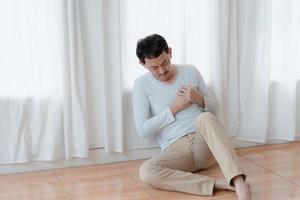 un hombre que toca su corazón, con un punto culminante rojo de ataque al corazón y otros concepto de enfermedad cardíaca, síntoma de ataque al corazón foto