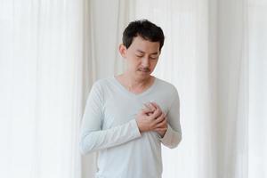 un hombre que toca su corazón, con un punto culminante rojo de ataque al corazón y otros concepto de enfermedad cardíaca, síntoma de ataque al corazón foto