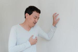 un hombre que toca su corazón, con un punto culminante rojo de ataque al corazón y otros concepto de enfermedad cardíaca, síntoma de ataque al corazón foto