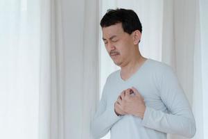 un hombre que toca su corazón, con un punto culminante rojo de ataque al corazón y otros concepto de enfermedad cardíaca, síntoma de ataque al corazón foto