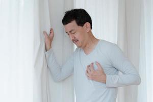 un hombre que toca su corazón, con un punto culminante rojo de ataque al corazón y otros concepto de enfermedad cardíaca, síntoma de ataque al corazón foto