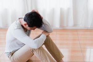 Depressed asian young man covering face by hands, crying alone at home, upset man sitting , feeling unhappy after quarrel or breakup, despair and lonely and panic , psychological problem concept photo