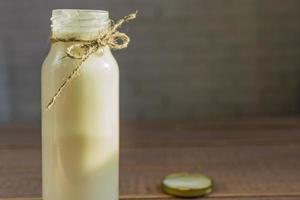 Open bottle of fresh milk on wooden background. Natural dietary product. photo