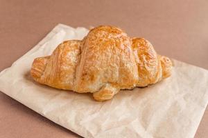 Close up of freshly baked french croissant on craft paper for breakfast. photo