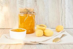 Home made organic apricot jam in glass jar and ripe apricots on wooden rustic table photo