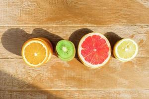 frame with slice of oranges, lemons, kiwi, grapefruit pattern on wooden background. Flat lay, top view with copy space. photo