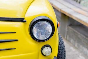 primer plano de un coche retro amarillo con faros redondos foto