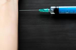 close up of syringe and wooman hand on wooden background photo