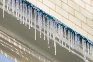 icicles hang from the roof of the building in a sunny winter day. photo